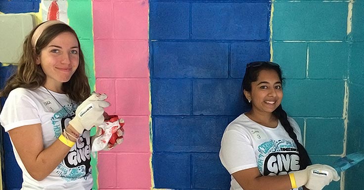 Two volunteers from Optus Rockcorps in front of a newly painted wall