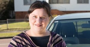 Hannah who has autism, in front of her car
