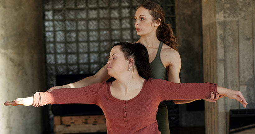 Yoga teacher showing a woman with Down syndrome a pose