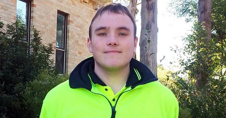 Aruma Supported Employee, Zac, standing outside in his high vis work clothes