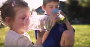 Two kids using their smell sense to sniff items in glass jars as part of a sensory activity