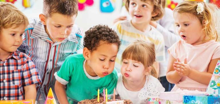 Group of kids at a birthday party blowing out candles