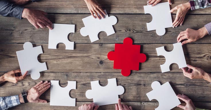 White puzzle pieces on a table with one red one in the middle