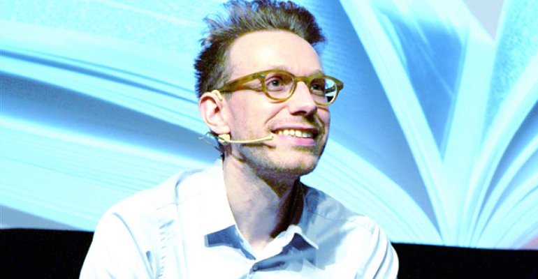 Daniel Tammet wearing a microphone and giving a speech