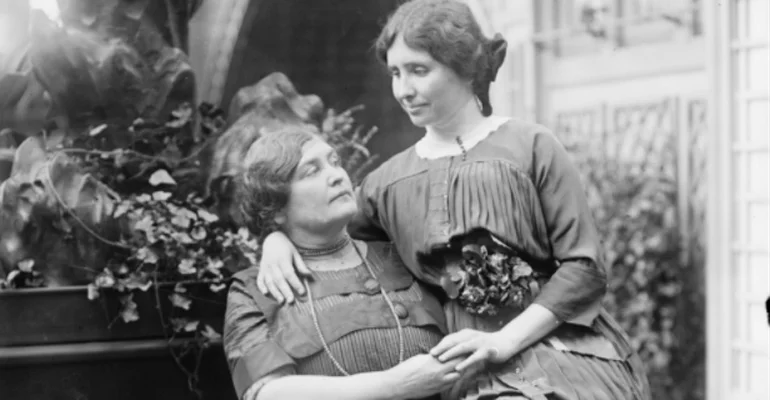 Helen Heller sitting on Anne Sullivan's lap and giving her a hug