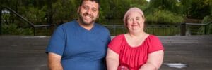 A Disability Support Worker sitting beside a lady with Down syndrome