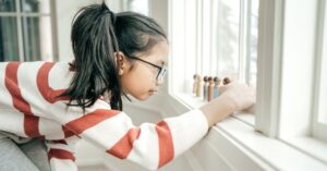 Girl with autism lining up wooden people in a row