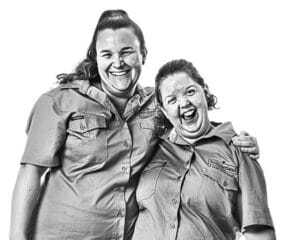 Two Aruma employees smiling with their arms around each other's shoulders