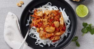 A bowl of pad Thai on a grey bench