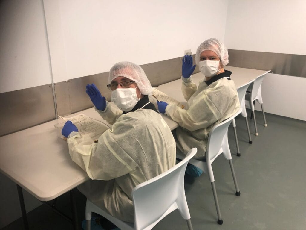 Two Aruma supported employee wearing gloves handling specialised packaging products at the Burleigh facility.