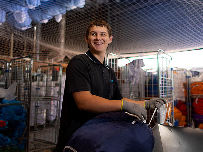 A supported employee working with laundry carts at Aruma Laundry social enterprise
