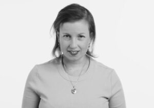 Elyce Shearer, one of Aruma's Human Rights Advisors posing with a big smile on her face in a black and white photograph.