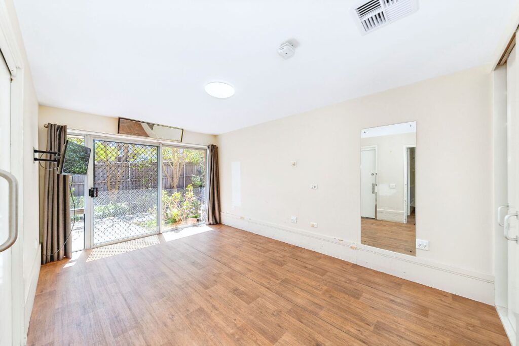 Spacious bedroom with timber floors, a large mirror and sliding glass door to the garden