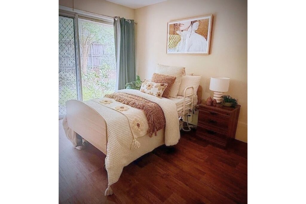Bedroom with a made single bed, artwork on the wall, timber floors and a window