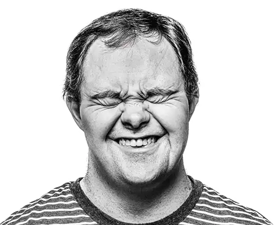 Customer of Aruma with Down syndrome laughing and wrinkling his nose