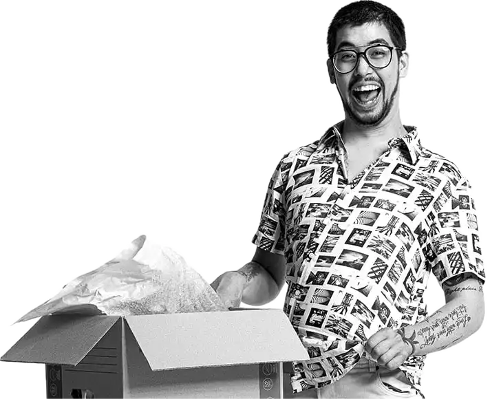 A young man smiling excitedly while unpacking a moving box in his new home.