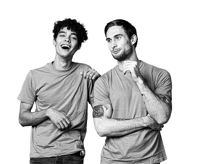 Two men smiling. The man on the left is leaning on the other one.