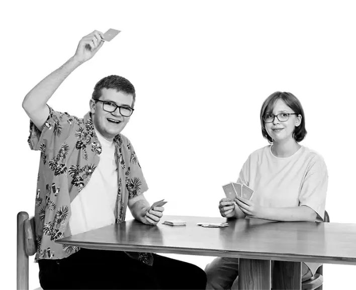 Two participants playing cards and laughing together during a respite accommodation stay