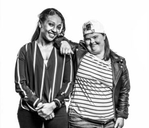 A support worker and participant laughing together, arms resting comfortably on each other's shoulders