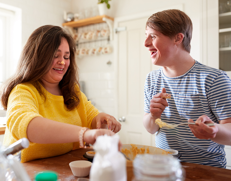 A participant and support worker having fun while baking as part of assistance with daily living