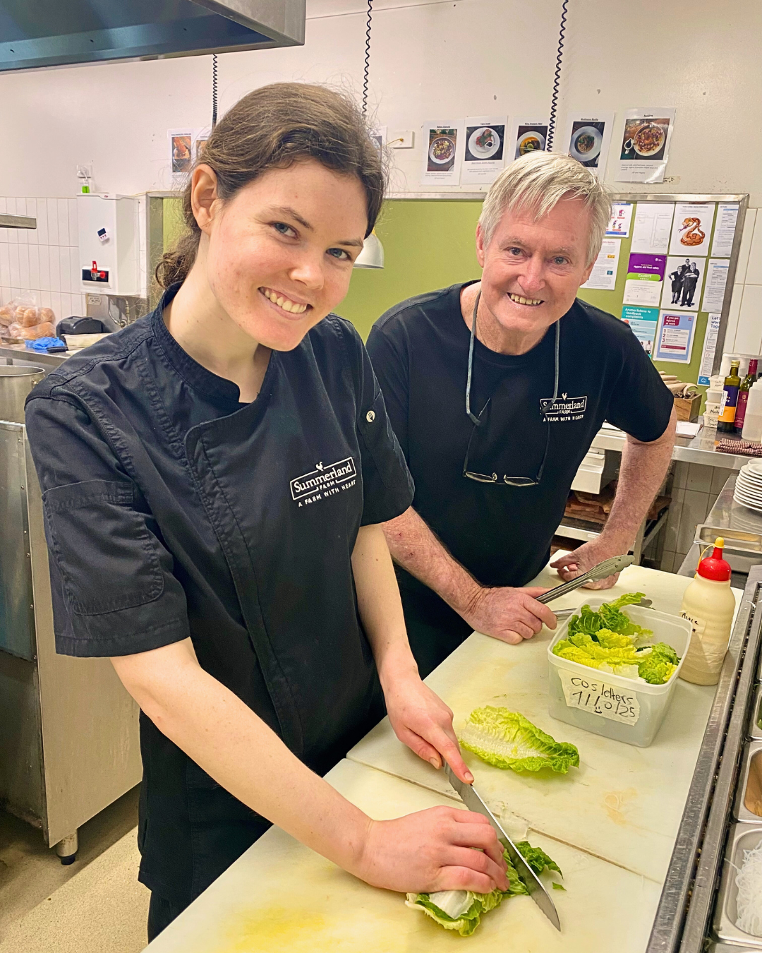 Charlotte chopping lettuce in the kitchen at Summerland Farm, working alongside a colleague.