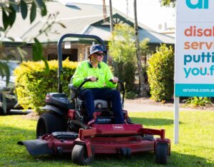 A supported employee in high-vis workwear mowing a lawn for Aruma Facilities Management supported employment