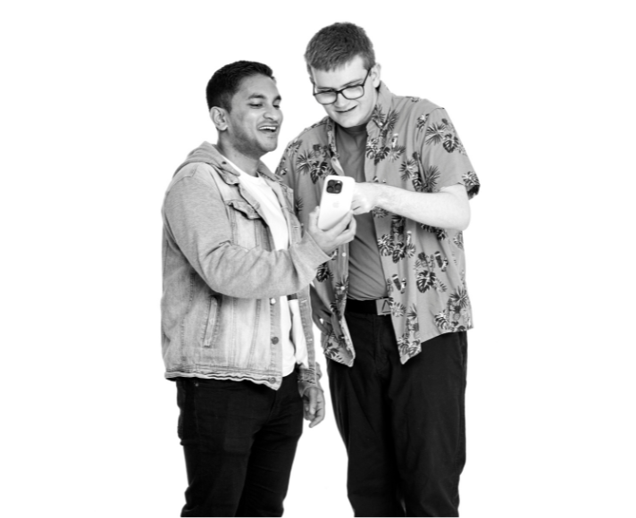 Aiden and his support worker smiling and looking at a phone together