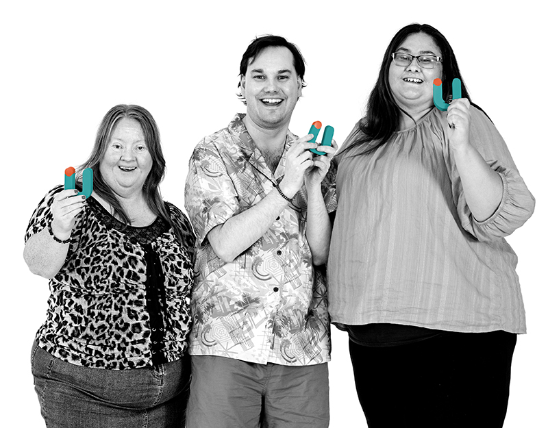 Three Aruma participants smiling and holding colourful Aruma logo letters