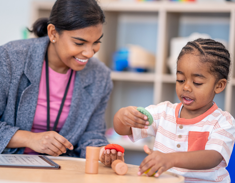 A young child engaged in play-based activities with a practitioner during positive behaviour support for children