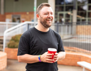 An adult participant smiling and enjoying a moment in the community, reflecting positive behaviour support services