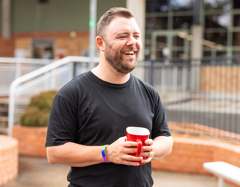 An adult participant smiling and enjoying a moment in the community, reflecting positive behaviour support services