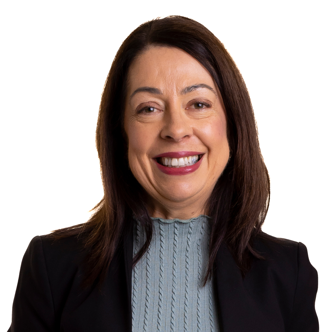 Heidi Clarris, Chief Customer Officer, smiling warmly. She is wearing a black blazer over a light blue knit top, with shoulder-length dark hair.
