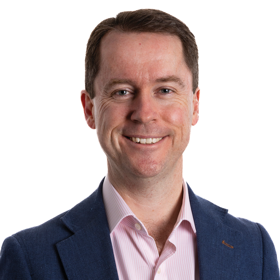 Martin Laverty, Chief Executive Officer, smiling. He is wearing a navy blazer over a pink striped shirt, with short brown hair.