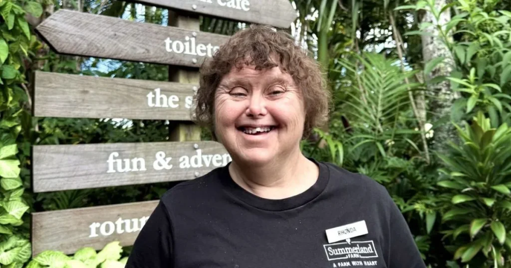 Ronda a team member of summerland farm social enterprise smiling to camera wearing a summerland farm uniform top.