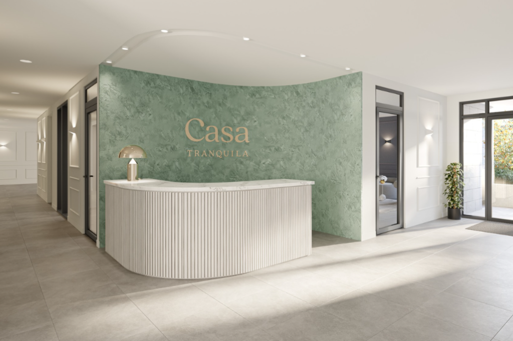 Concierge lobby Hotel-style concierge lobby at Casa Tranquila with a curved fluted reception desk, sage green feature wall and gold Casa Tranquila signage.