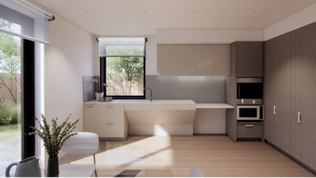 Render of the kitchen inside a Ringwood East SDA home, showing an accessible height benchtop, built-in oven, timber cabinetry, large window with garden views and timber flooring.
