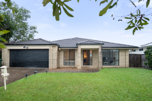 Front exterior of the Pacific Pines SIL home, a single-storey brick house with a double garage, tiled roof and front lawn.