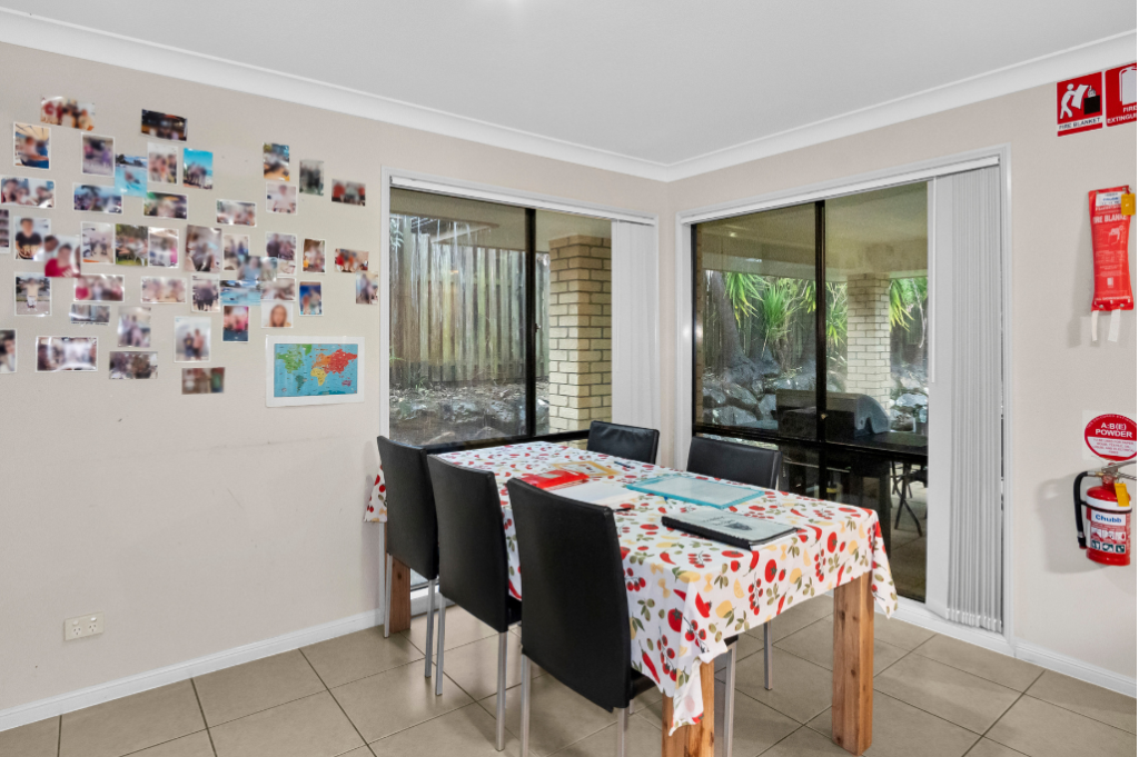 Dining area inside the Pacific Pines SIL home, with a dining table and chairs and sliding doors to the covered patio.