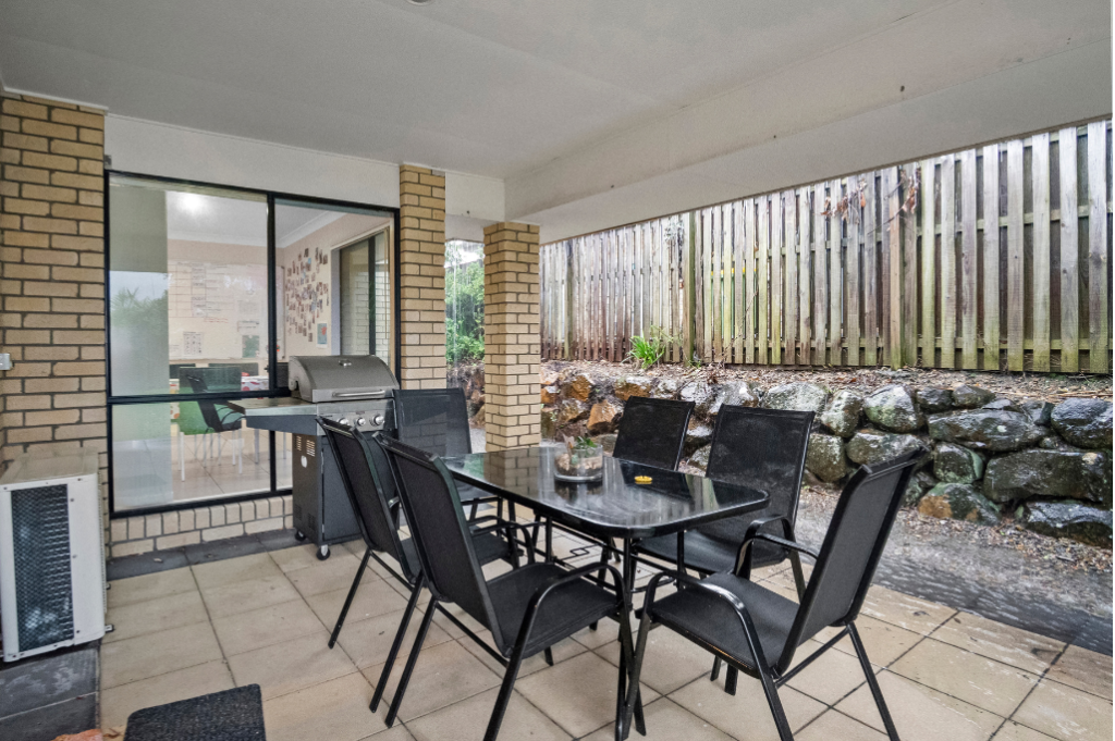 Covered patio at the rear of the Pacific Pines SIL home, with an outdoor dining setting and BBQ.