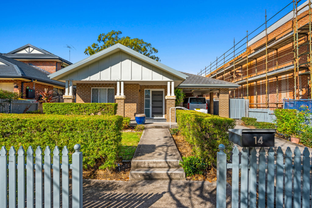 Front exterior of the Strathfield SDA home from the street, showing the brick facade, gabled entry, front path with steps, landscaped hedges, picket fence and letterbox.