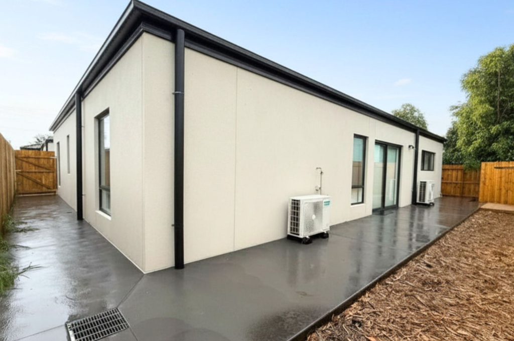 11. Rear exterior of the Sale SDA home, showing the paved courtyard, air conditioning units and sliding door access to the living area.