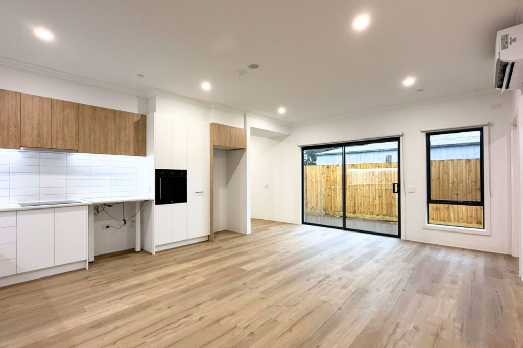 5. Living area inside the Sale SDA home, showing sliding doors opening to the paved backyard, timber-look flooring and wall-mounted air conditioning.