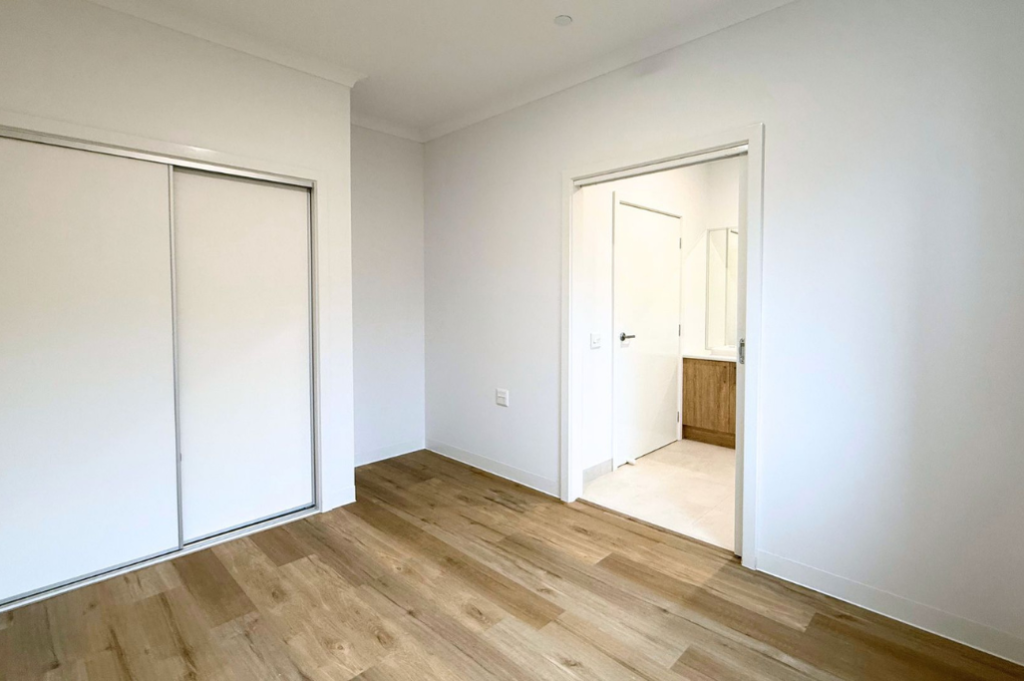 6. Bedroom inside the Sale SDA home, with a built-in mirrored sliding wardrobe and doorway leading to the private accessible ensuite.