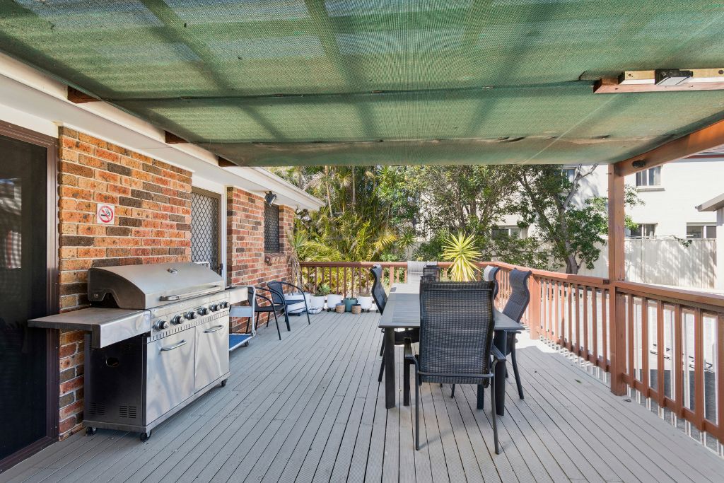 Covered rear deck of the Albion Park SIL home, with an outdoor dining setting, BBQ and views over the backyard.