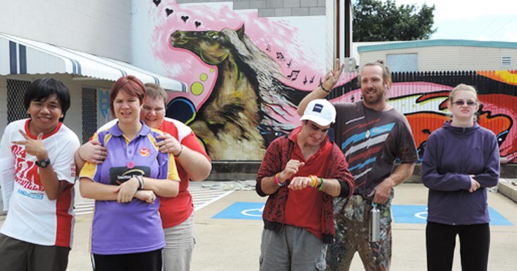 Aruma customers and a Disability Support Worker in front of their new mural