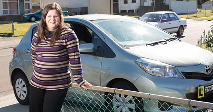 Hannah who has autism standing with her car outside