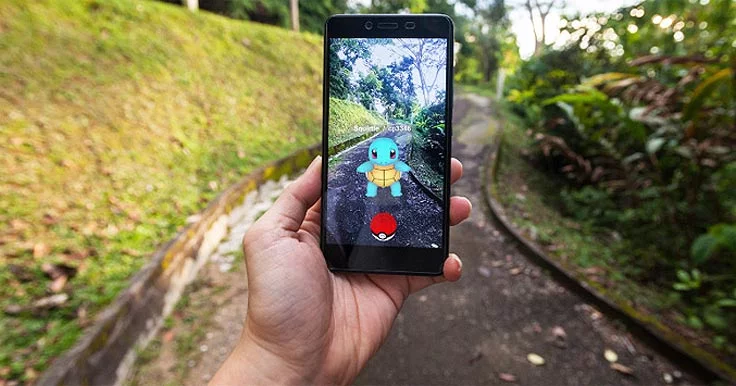 Person's hand holding a smartphone with Pokemon Go on the screen