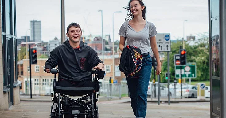Woman and man in wheelchair chatting on the street
