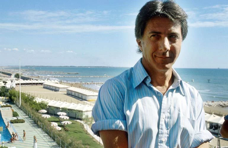 Dustin Hoffman standing outside with a view of the beach