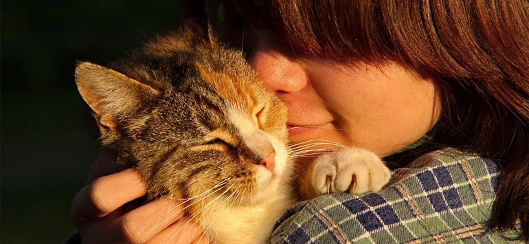 A woman hugging a cat closely
